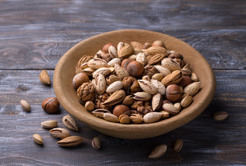 Variety of nuts in wooden bowl over wooden table. almonds, walnuts, hazelnuts, pistachios. rustic style. horizontal