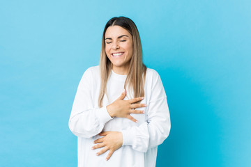 Young caucasian woman isolated laughs happily and has fun keeping hands on stomach.