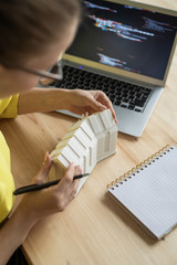 Young female architect working over new residence model in front of laptop