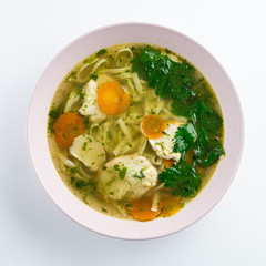 Classic chicken noodle soup with carrot and parsley isolated on white