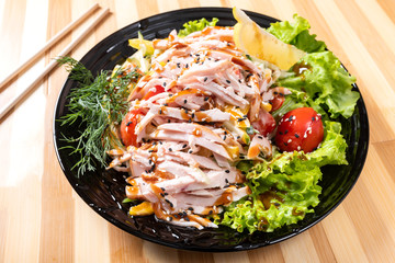 Japanese chicken salad on a black plate.