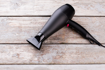 Black hair dryer on wooden background. Electric hair dryer on vintage wooden surface.