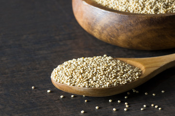 White quinoa seeds in wooden spoon and bowl on rustic background ( Chenopodium quinoa ), cereal healthy vegetarian food gluten free to lose weight