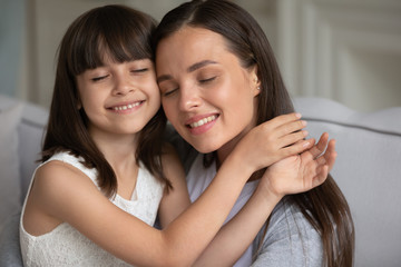 Mother cuddle daughter people with closed eyes enjoy tender moment