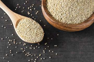 White quinoa seeds in wooden spoon and bowl on rustic background ( Chenopodium quinoa ), cereal healthy vegetarian food gluten free to lose weight