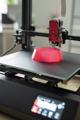 Printhead of 3d printer over part of pink round object on working surface