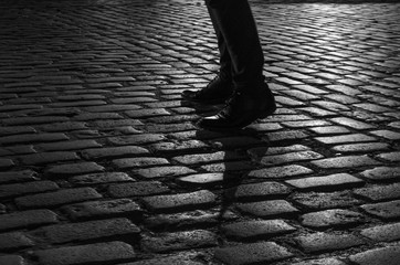 silhouette of a person's shoes while walking on the cobblestone