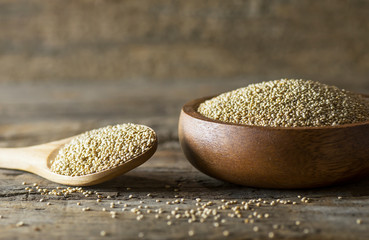 White quinoa seeds in wooden spoon and bowl on rustic background ( Chenopodium quinoa ), cereal healthy vegetarian food gluten free to lose weight