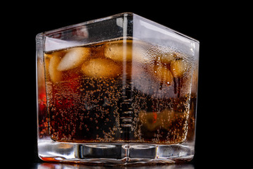 A cold refreshing drink with ice in a glass. Ice cubes and a sweet cold drink in a glass dish.