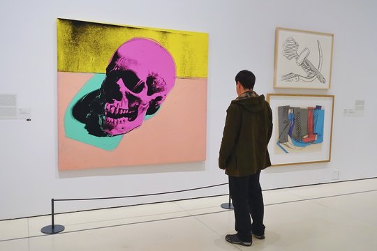 MADRID, SPAIN - APRIL 05, 2018: Visitors in the CaixaForum Madrid consider pictures at the exibition Andy Warhol "Warhol. Mechanical Art."