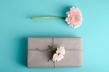 Beautiful gift boxes wrapped in simple brown kraft paper decorated with live gerbera on a pastel background. Spring festive romantic concept.