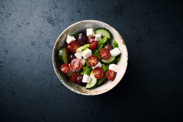 Salad with Kalamata Olives, Cucumber Cherry Tomatoes and Feta Cheese on black Stone Background. Healthy Snack Idea. Top view. Copy space. 