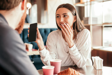 Cheerful woman showing social media to boyfriend