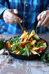 Selective focus. Chef hands mix pasta with vegetables and basil. Cooking vegan paste. Italian Cuisine.