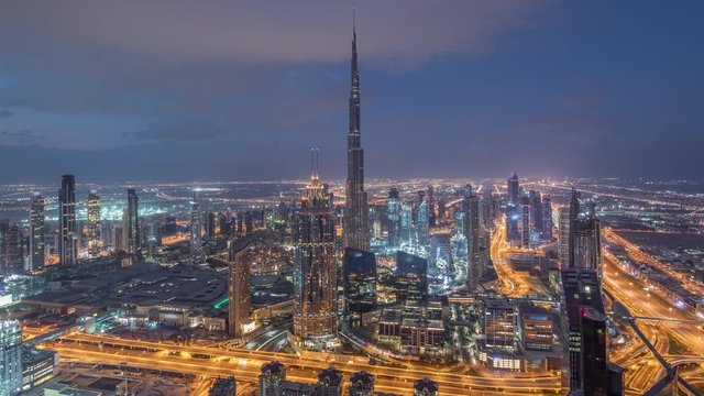 Dubai Downtown skyline futuristic cityscape with many skyscrapers and Burj Khalifa aerial night to day transition timelapse. Morning panorama with modern towers and construction from rooftop before