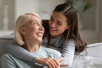 Grown up daughter embracing elderly mother laughing enjoy time together