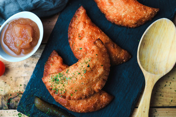 Four small pasty homemade with applesauce on slate plate. Top view, no people. Food concept