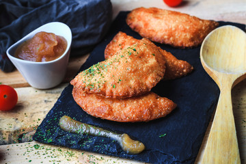 Four small pasty homemade with applesauce on slate plate. Front view, no people. Food concept