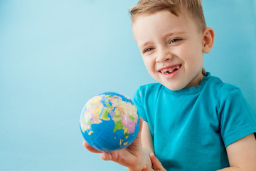 Little boy holding a globe on blue background