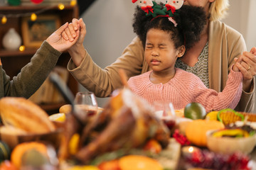 Family praying before dinner in thanksgiving dinner.