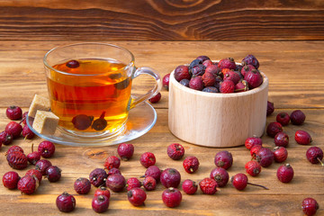Rose hips.Dried rosehip berries with a cup of aromatic rosehip drink on a wooden background. Healing berries.