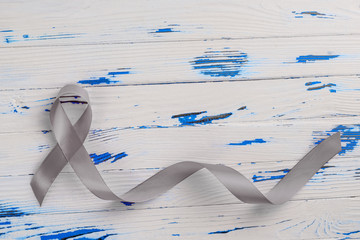 grey ribbon on a wooden table. Parkinson's disease or brain cancer awareness concept