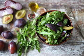Selective focus. Healthy salad with arugula and plum in a bowl.