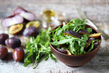 Selective focus. Healthy salad with arugula and plum in a bowl.