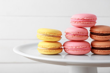 Stand with different tasty macarons on white background, closeup