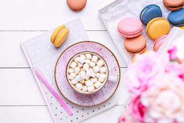 Cup of hot chocolate with tasty macarons on table