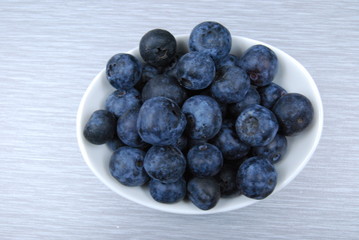 Overhead view of dish of fresh blueberries on gray table