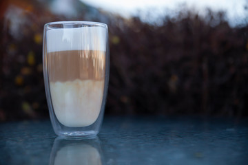Transparent cup with latte, which stands on a table on the street
