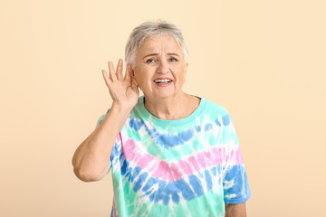 Senior woman with hearing problem on light background