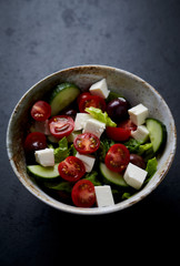 Salad with Kalamata Olives, Cucumber Cherry Tomatoes and Feta Cheese on black Stone Background. Healthy Snack Idea. Close up.