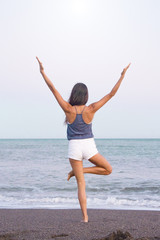 Young athlete woman practicing yoga on the beach