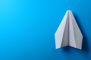 Airplane made of white paper on a blue background.