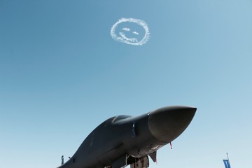 B-1 Lancer military aircraft on display with smiley face drawn in sky above at EAA Airventure...