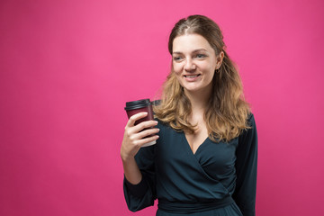 Glamor woman in a dark blue dress with a drink of coffee on a pink background