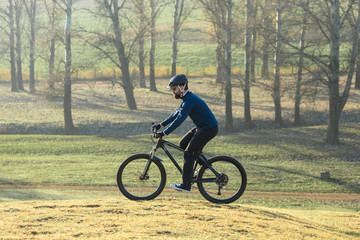 Fototapeta premium Cyclist in pants and fleece jacket on a modern carbon hardtail bike with an air suspension fork. The guy on the top of the hill rides a bike.
