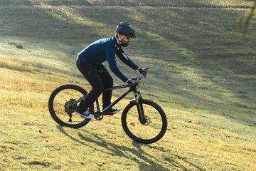 Cyclist in pants and fleece jacket on a modern carbon hardtail bike with an air suspension fork. The guy on the top of the hill rides a bike.