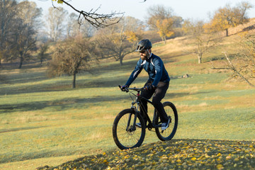 Naklejka premium Cyclist in pants and fleece jacket on a modern carbon hardtail bike with an air suspension fork. The guy on the top of the hill rides a bike.