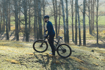Obraz premium Cyclist in pants and fleece jacket on a modern carbon hardtail bike with an air suspension fork. The guy on the top of the hill rides a bike.