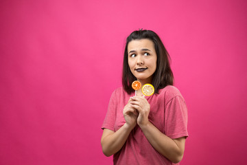 Portrait of lovely sweet beautiful cheerful woman with straight brown hair holding a lollipop near the eyes.