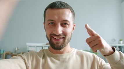 Playful office worker is taking selfie at work looking at camera showing thumbs-up and hand gestures and tongue smiling having fun. People and photos concept.