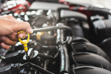 Man service mechanic maintenance inspection service maintenance car Check engine oil level car in garage showroom dealership blurred background.