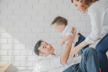 Fototapeta premium Asian Japanese Family father mother son wearing white shirt carrying child posing for photo on bedroom in white room.To keep memories moment cuteness of son in childhood
