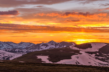 Obraz na płótnie Canvas Sunset Mountain Road - Colorful Spring sunset clouds over Trail Ridge Road, winding along a steep ridge, with snow peaks of Never Summer Mountains in background. Rocky Mountain National Park, CO, USA.