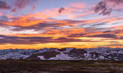 Obraz na płótnie Canvas Sunset RMNP - A panoramic view of colorful Spring sunset sky over snow-capped high peaks of the Continental Divide at top of Rocky Mountain National Park, Colorado, USA.