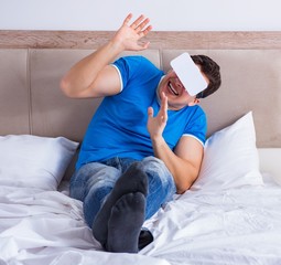 Obraz na płótnie Canvas Young man in bed wearing a vr virtual reality head set