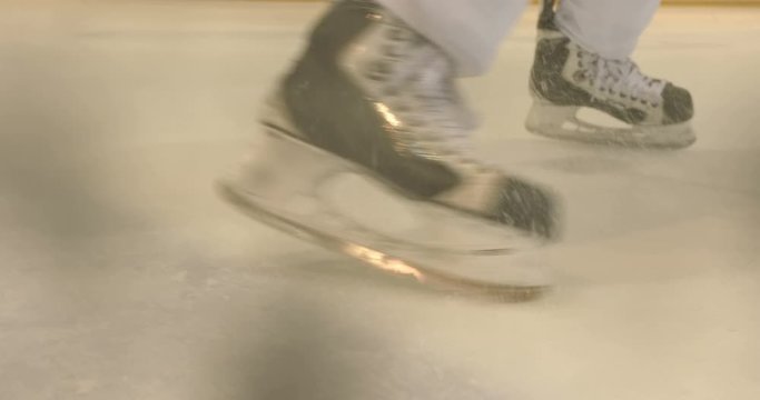 A professional hockey player accelerates on ice and brakes sharply on his skate, forming a lot of ice in the form of dust